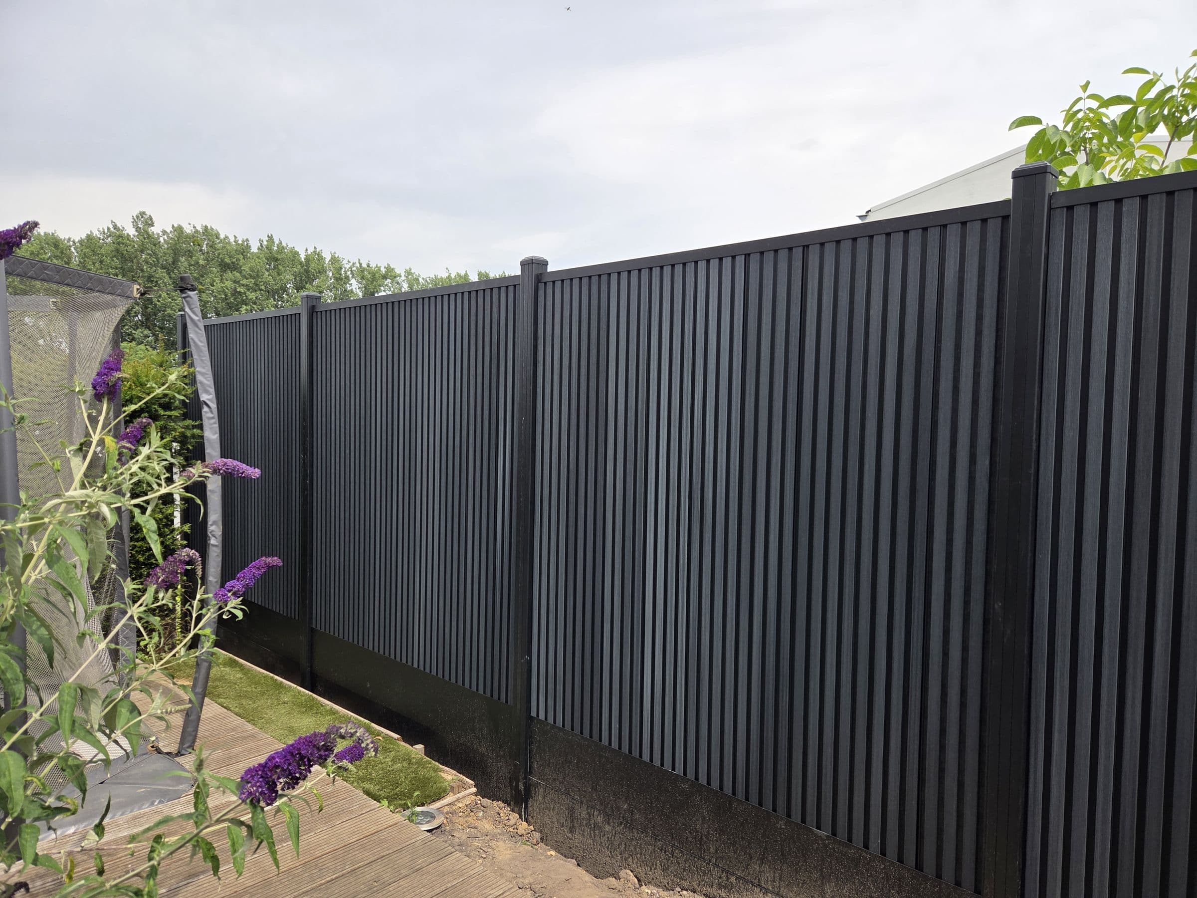 Composiet antraciet: Antraciet schutting achter een border