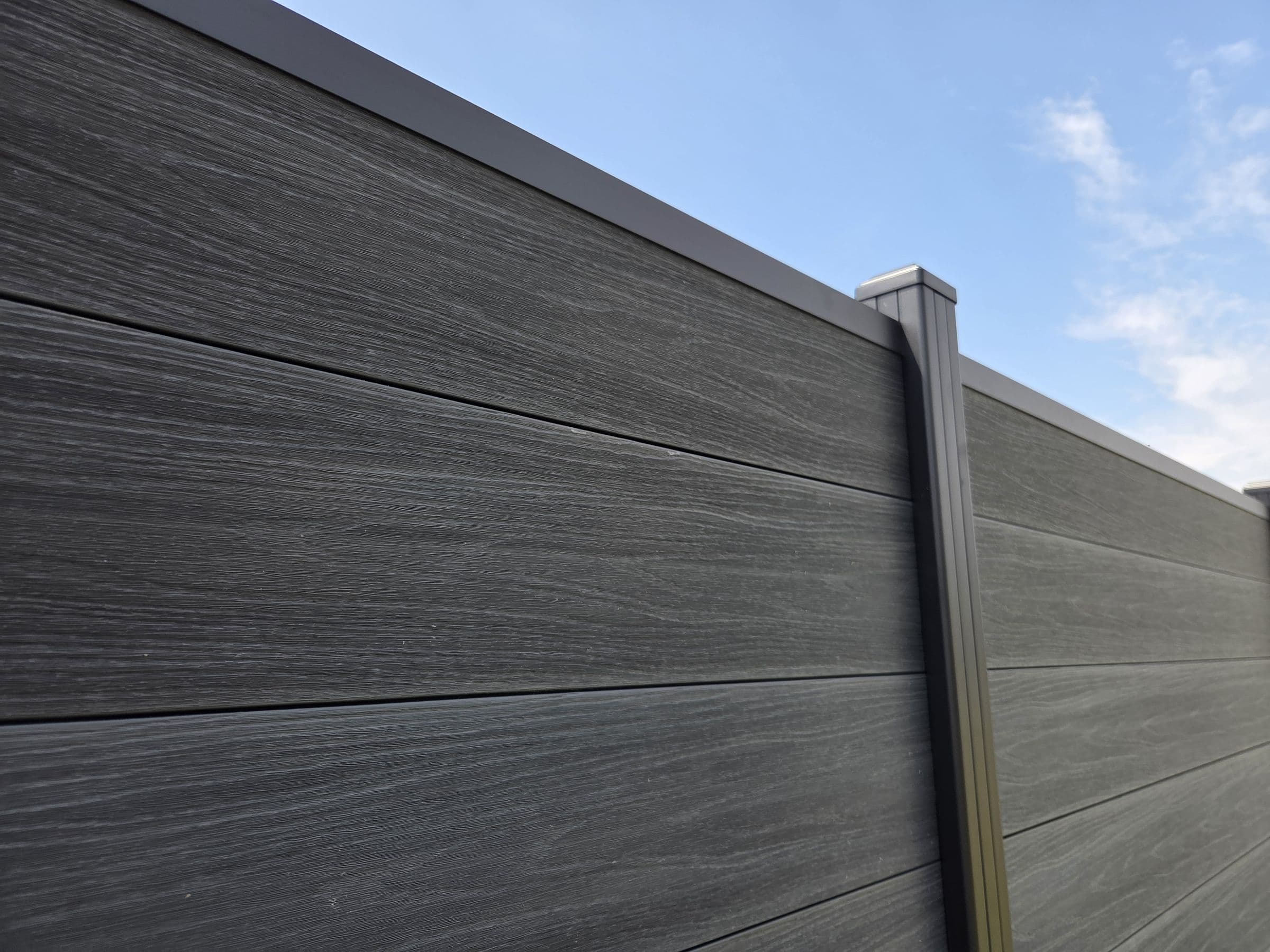 Composiet antraciet: Antraciet planken en zwarte aluminium paal van dichtbij