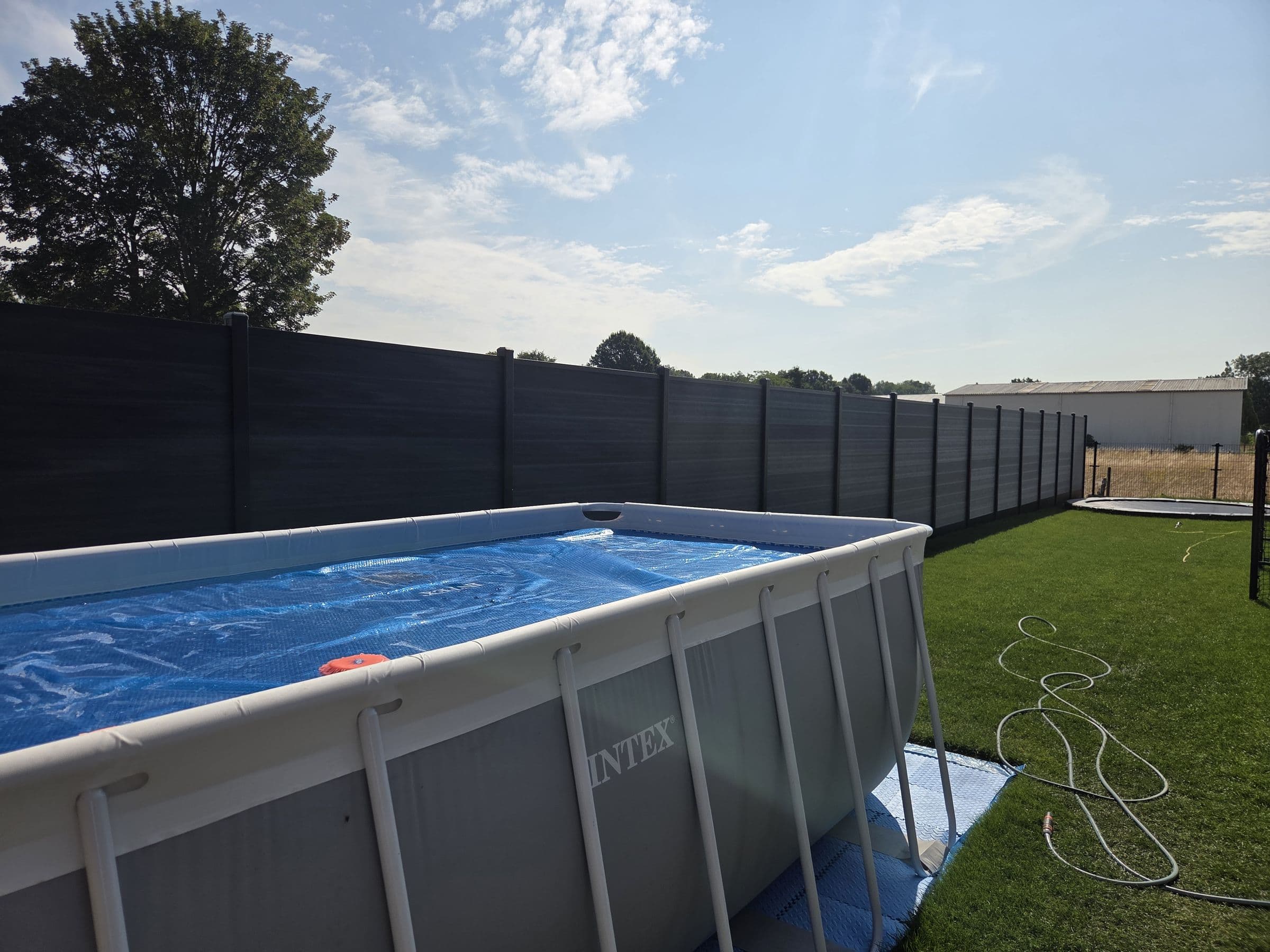Composiet antraciet: Antraciet schutting rond een tuin met zwembad