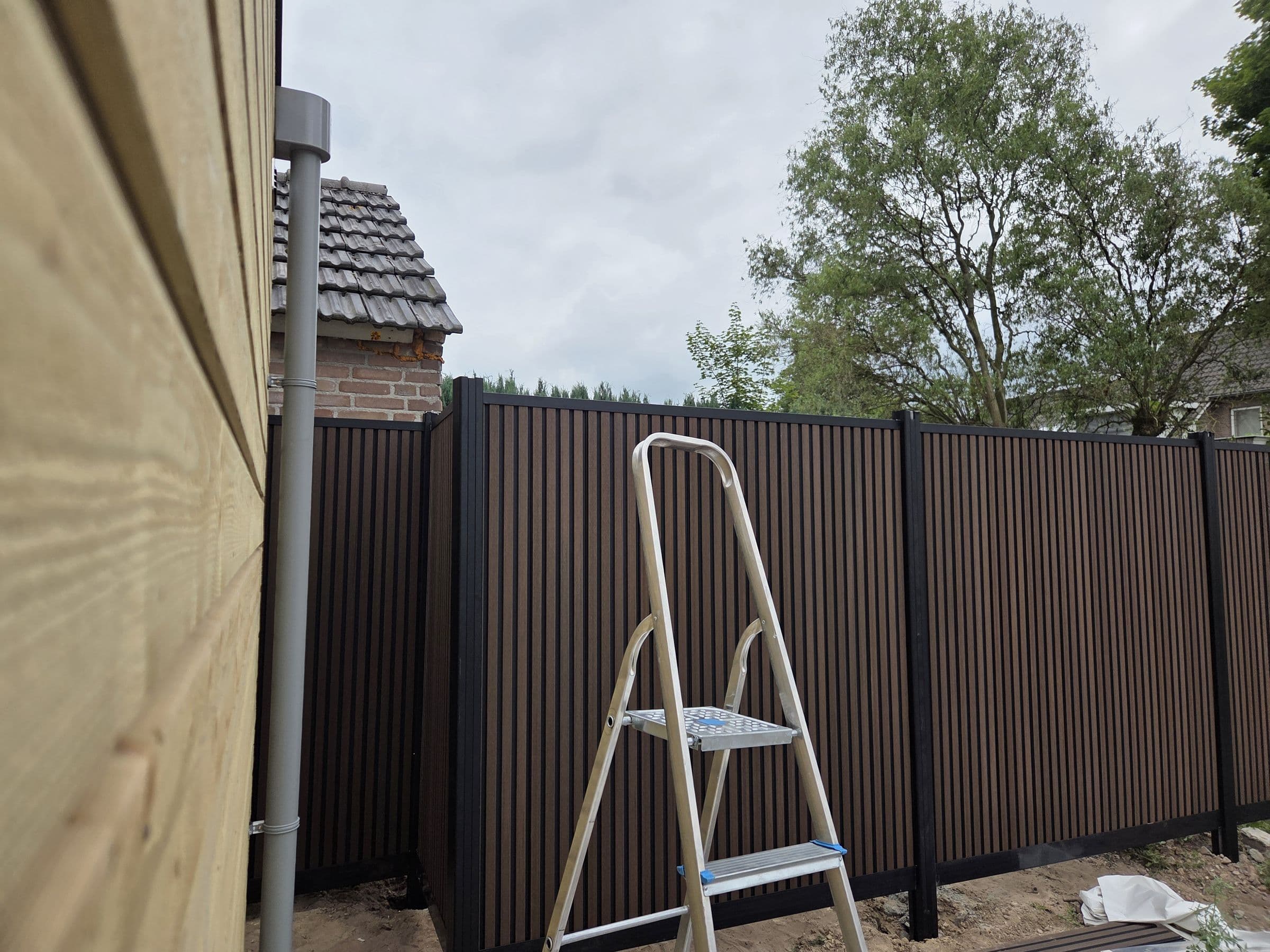 Composiet houtlook: Bruine composiet schutting in een tuinhoek